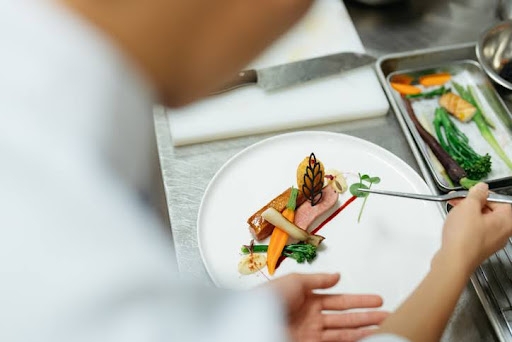 Young Asian Chinese chef decorating and preparing gourmet dish before serving