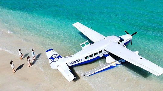 blade-sec-img-03 Seaplane parked on a tropical beach beside crystal-clear turquoise water