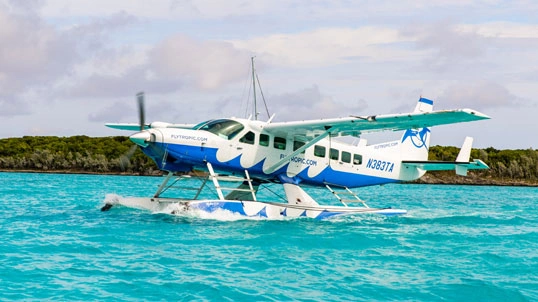 blade-sec-img-04 Seaplane cruising across clear turquoise tropical waters during flight transfer
